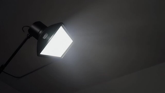 A bright light shines from a lamp on the ceiling in darkness.
