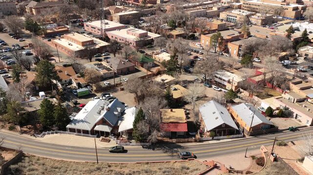 A high-altitude drone perspective overlooks the iconic adobe rooftops and urban sprawl of Santa Fe. This 4K view captures the city's unique architectural harmony and mountain horizon.