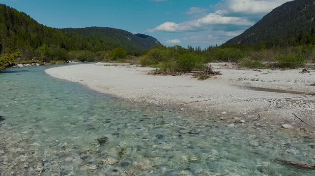 Crystal clear turquoise Isar river with white pebble beach and mountains, Bavarian Alps, Germany