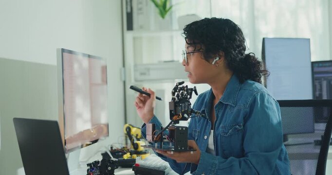 Young African American female robotics engineer discussing mechanical part on video call in laboratory. Remote work, virtual training, online meeting, future technology, technical support concept.