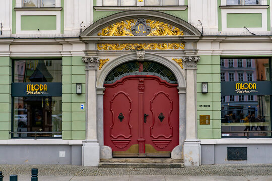 The historic Oppenheim House in Wroclaw featuring Młoda Polska bistro, showing an ornate portal with gold leaf decorations and iconic red doors on the city's Solny Square.