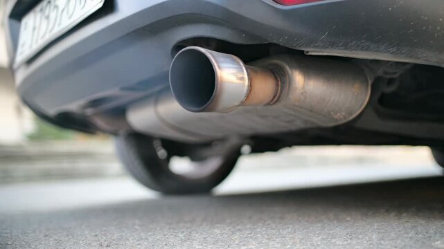 Close-up of a car exhaust pipe emitting fumes, highlighting vehicle pollution and environmental concerns