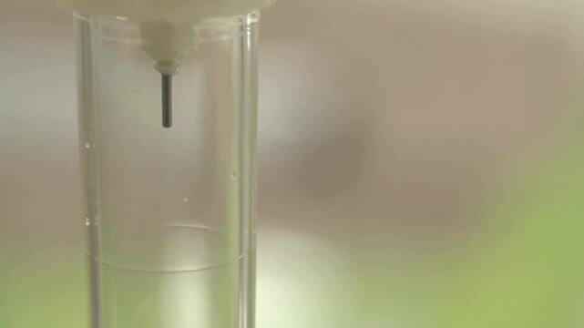 Close-up of intravenous saline solution in medical clinic in light bright interior IV drips through drip chamber NSS drip ready to be infused