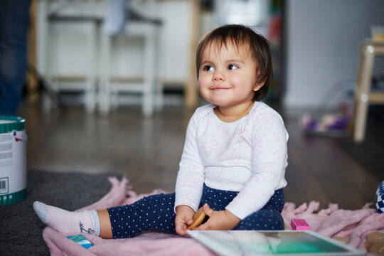 Cute baby girl sitting on the floor at home