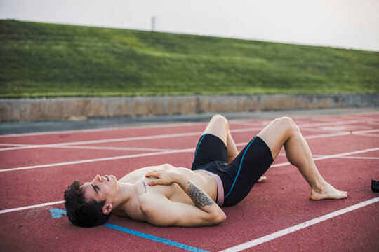 Athlete lying resting on a tartan track after finishing a race