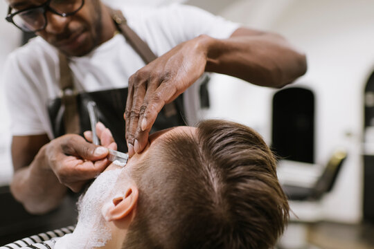 Man getting his beard shaved with razor in barber shop