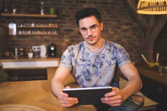 Portrait of young man using tablet in kitchen at home