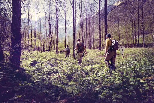 Slovenia, Bovec, three anglers walking in forest towards Soca river