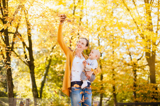 Mother and baby girl having fun with leaves in autumn