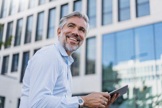 Smiling mature businessman using tablet in the city