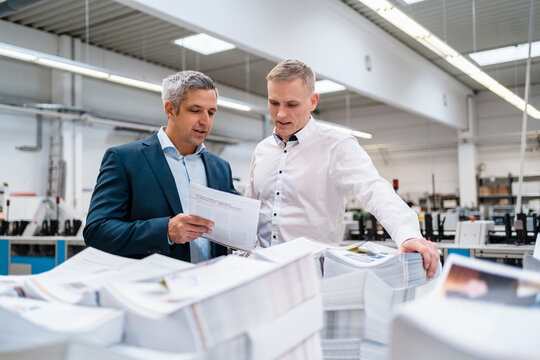 Two businessmen discussing paper in a factory