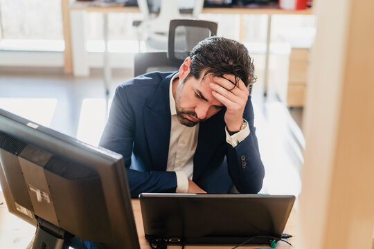 Frustrated businessman sitting at desk in office