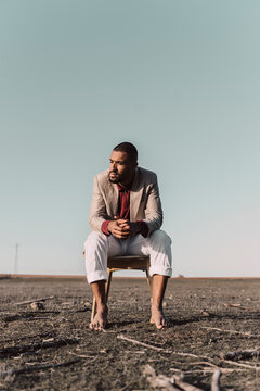 Young man sitting on chair in barren land