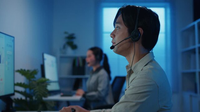 Gen z Asia young call center team or customer support service executive use computer and microphone headset work technical e commerce support in late night office. Telemarketing or sales job concept.