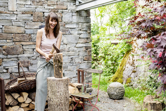 Screaming woman chopping wood in front of a house