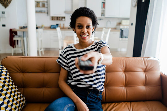 Portrait of smiling young woman watching Tv at home