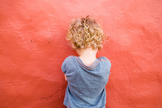 Back view of little boy standing in front of red wall