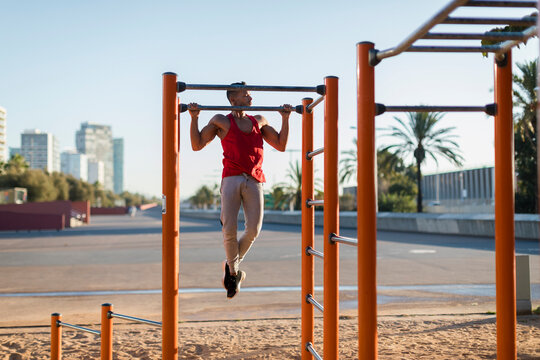 Fit man working out in climbing parcour, doing pull ups