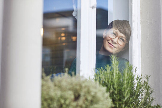 Smiling woman at home looking out of window