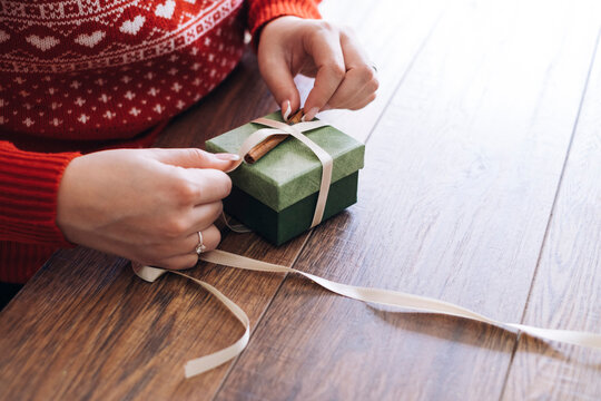 Woman's hands decorating Christmas present