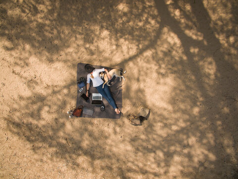 Bird's eye view of woman lying on blanket with dog and utensils