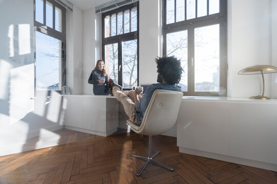 Smiling couple sitting in minimalist empty room talking