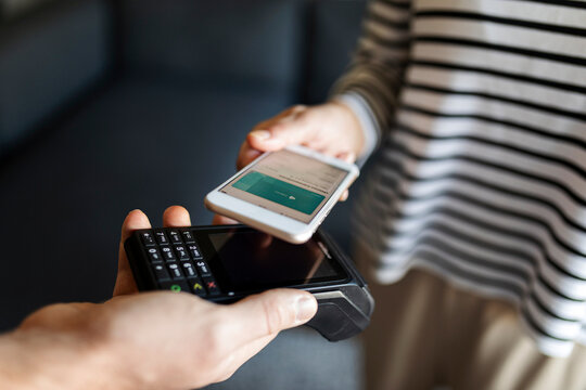 Close-up of woman paying with mobile phone at home