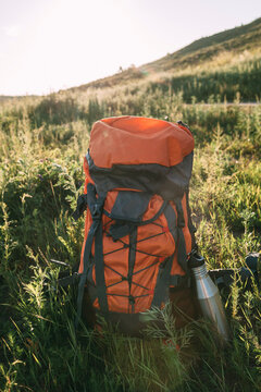 Backpack and thermos flask on a meadow