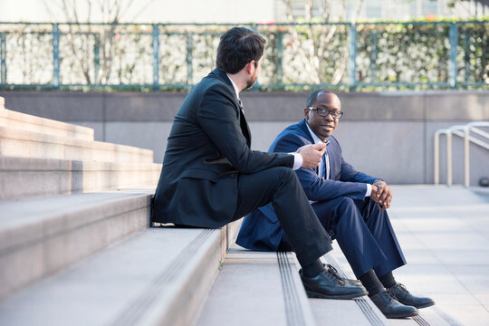 Two businessmen sitting on stairs talking