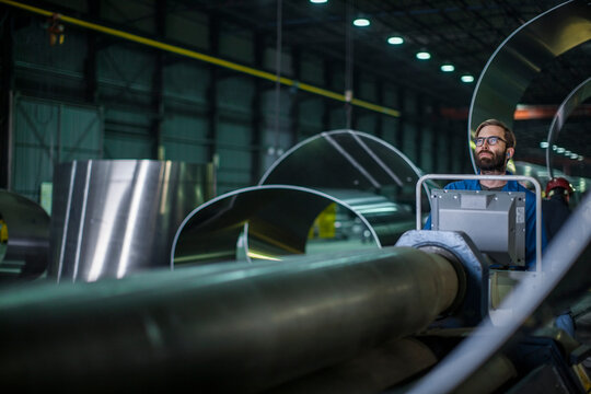 Worker operating machinery at control panel in steel factory