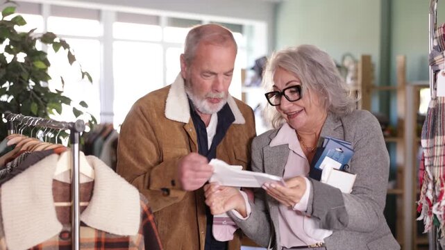 Mature couple spend time in shop and choose socks. Changing wardrobe, shaping style of clothing. Designer clothes, clothing of world brands