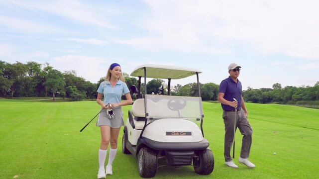 Asian golfer team ride in golf cart together on a scenic golf course. 