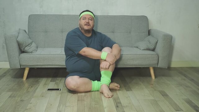 Overweight man lifting knees up and out to sides in funny home fitness workout. Chubby active person doing physical exercises, cardio or warmup training in living room. Happy fay man
