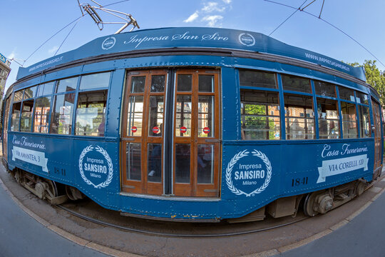 MILAN, ITALY - JUNE 22, 2018: Retro blue tram with passengers on the street in Milan. A symbol of the city, traditional ATM Class 1500 is a series of trams used from 1927. Wide angle view.