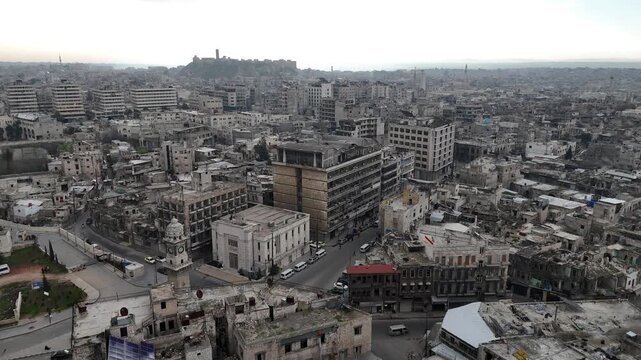 Cinematic aerial drone shot of Aleppo, Syria, featuring the historic Bab al-Faraj Clock Tower and the ancient Citadel on the horizon