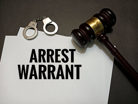 Arrest warrant document with judge gavel and handcuffs on desk representing legal authority, criminal justice system, police enforcement, investigation, and law order concept.