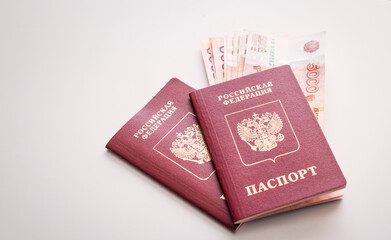Red passport and stack of Russian ruble banknotes on white background, travel money, finance, document, personal savings.