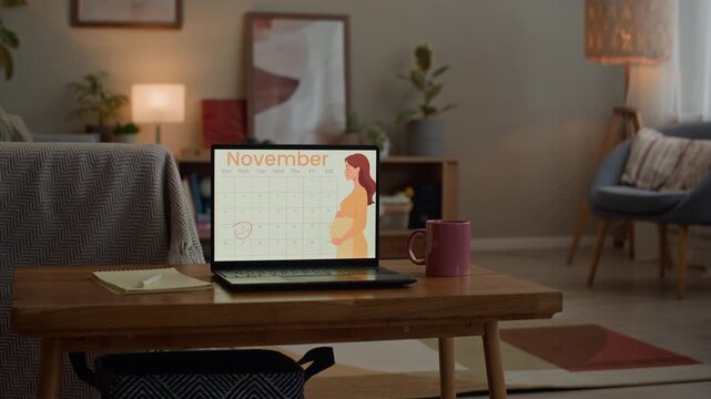 Medium shot with focus on digital laptop screen with pregnancy tracking application on wooden table in modern home workspace