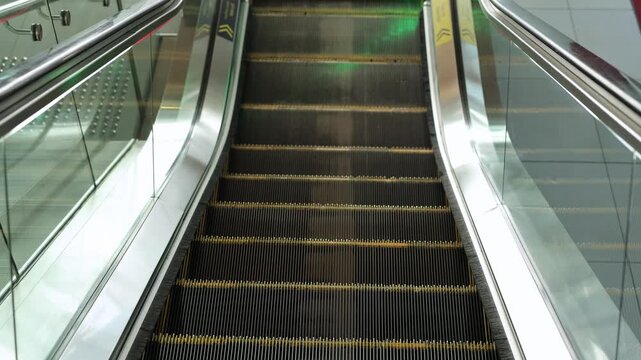 Empty modern escalator with green handrail lighting in an underground station.