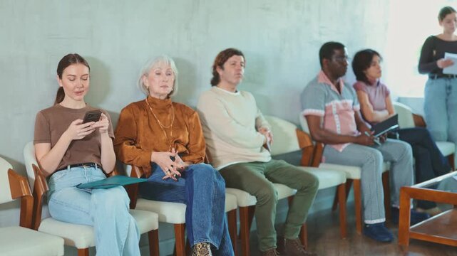  Group of people are waiting for their turn for an interview at the reception area in the office. Job seekers preparing for an interview with a recruitment manager at a marketing company