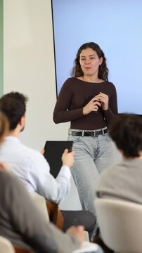 Young woman teacher gives lecture to group in lecture hall. High quality 4k footage