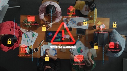 Team Meeting with System Warnings and Alert Icons Overlaid on Table with Laptops and Charts for...