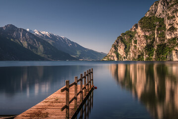 Obraz premium Wooden pier on Lake Garda near Riva at sunrise