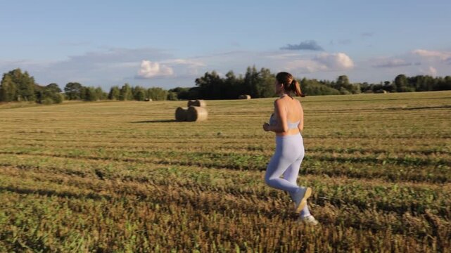 young woman jogging in a field on a sunny day in summer