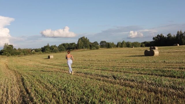 young woman jogging in a field on a sunny day in summer