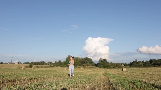 young woman jogging in a field on a sunny day in summer