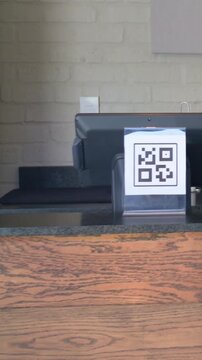 Vertical video: After talking man in mustard jacket hoodie exiting cafe counter with QR napkin