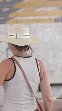 Vertical video: Replying to hello, woman in hat laughing, walking at home, strap moving, copy space