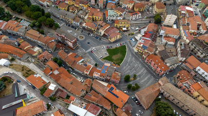 Aerial view of a vibrant town with colorful buildings, terracotta roofs, and a central green patch, showcasing urban architecture. It's the main square of Rionero in Vulture, in Basilicata, Italy.