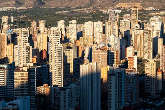 Strong sunlight creates deep contrast on the Benidorm Spain skyline with modern urban architecture and skyscrapers backed by a mountain and shadows